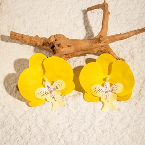 Macro detail of vibrant yellow orchid flower earrings with purple speckled center