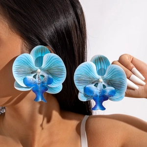 Detailed close-up of large blue orchid earrings featuring textured petals on model