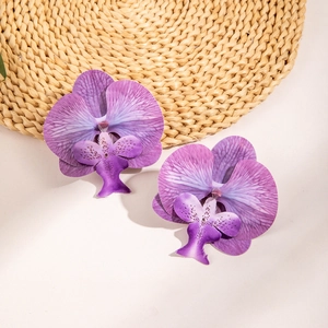 Macro shot of purple orchid earrings showing lifelike petal textures and gradient colors