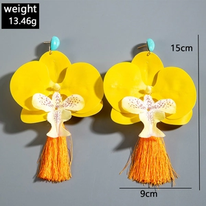 Detailed view of yellow orchid earrings with turquoise stones and long orange silk tassels