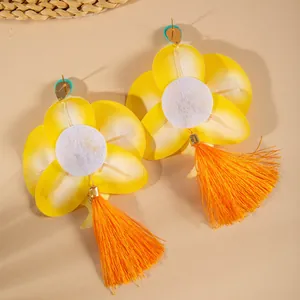 Detail of tropical orchid earrings with yellow-white petals and long orange tassels