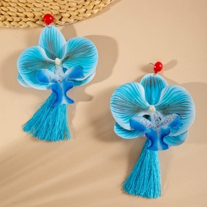 Detailed macro view of blue orchid earrings with colorful tassels and red bead accents
