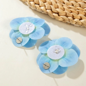 Detail of blue gradient fabric orchid earrings with silver needle on summer beach background