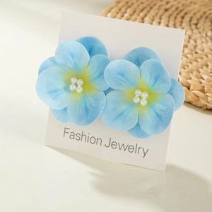 Close-up of blue sunflower earrings with pearl center on a fashion display card