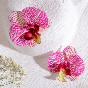 White straw sun hat featuring vibrant pink spotted orchid floral decorations on top