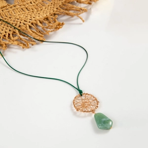 Detailopname van geweven gouden dromenvanger hanger met groene harsdruppel op zomerhoed