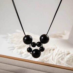 Detailopname van glanzend zwarte kralenketting met ronde Mickey-vormige bedeltjes