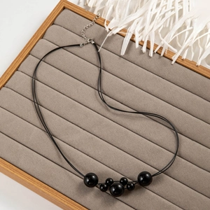 Detail van de minimalistische zwarte kralenketting met zilveren verlengketting en karabijnslot