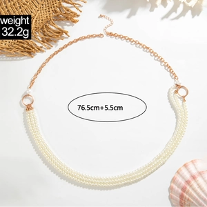 Detail van gelaagde witte parels en gouden ketting taille riem met een karabijnsluiting