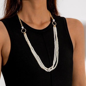 Detail van een meerlaagse witte parelketting met vergulde metalen ketting op model
