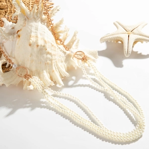 Detail van gelaagde parelketting met gouden ringen, zeeschelpen en zeesterren decoratie