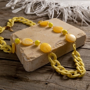Detail van gele matte schakelketting met marmeren textuur hangers op een steen