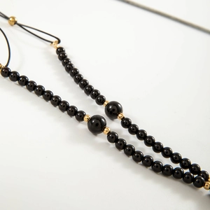 Gedetailleerde close-up van glanzende zwarte kralen en gouden spacers van deze lange ketting