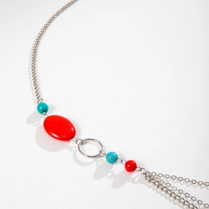 Detail van zilveren legering ketting met rode edelsteen en bohemien stijl franjes
