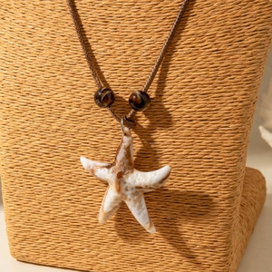 Detail van zeester hanger met marmeren textuur en bruin gevlochten halsketting