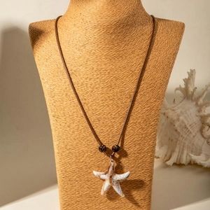 Detail van de zeester hanger aan een bruine geweven ketting met kralenaccent