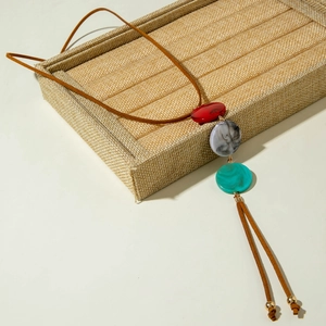 Detail van een bohemian lange ketting met kleurrijke harsbedeltjes en suède kwastjesfranje
