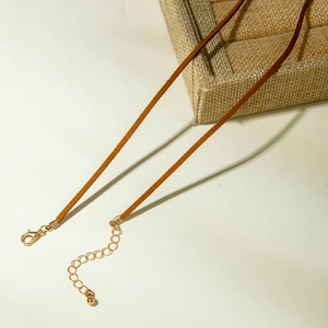 Detail van de bruine suède halsketting met gouden karabijnsluiting en verlengketting