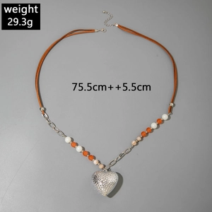 Detail van de bohemien hartketting met oranje kralen en bruine leren koordconstructie