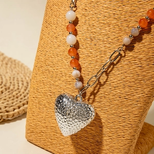 Detail van de boho hart hanger met gehamerde textuur en kleurrijke kralen ketting