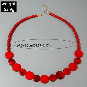 Detail van rode kralenketting met grote getextureerde schijven en gouden verlengketting
