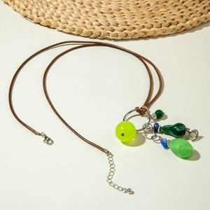 Detail van kralenketting met groene hangers, metalen bloemen en bruine lederen koord