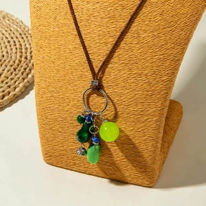 Detail van boho ketting met groene kralen en zilveren bloem op strooien nekmodel gepresenteerd
