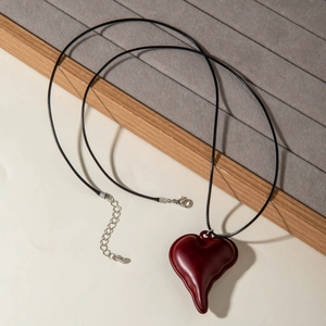 Detail van een smeltende hartvormige hanger van rode hars aan een zwart koordsnoer