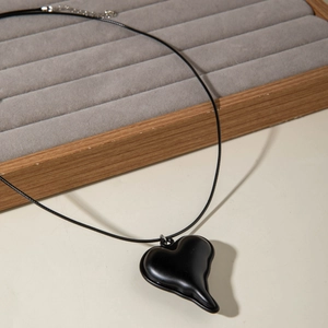 Detail van een matzwarte lava-hart hanger met een geweven koord en een metalen sluiting