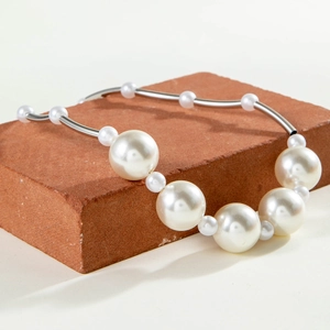 Fashion oversized pearl necklace with curved silver metal tubes on a natural stone base