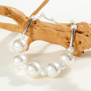 Fashionable oversized faux pearl necklace with silver metal tubes on rustic wood display