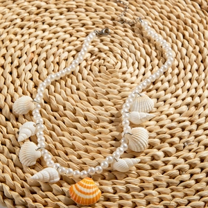 Island style pearl beaded necklace featuring natural white seashells and orange scallop pendant