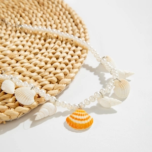 Marine style pearl necklace with shell and scallop pendants on a woven background
