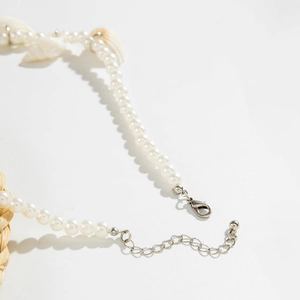 Close-up of pearl necklace featuring shell pendant with silver lobster clasp and chain