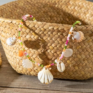 Detail of bohemian shell necklace with colorful beads on a rustic woven basket