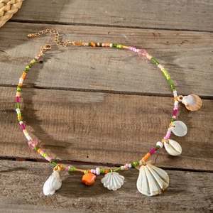 Detailed shot of bohemian beaded necklace with natural seashells on dark vintage wood