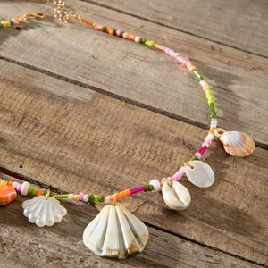 Detail of colorful beads and shell charms on beach necklace over dark wood texture