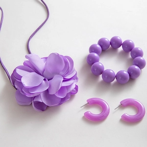 Dettaglio della collana con fiori in tessuto viola con bracciale di perline e orecchini a cerchio