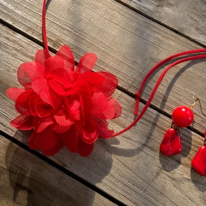 Dettaglio della collana con rose di stoffa rossa e orecchini di perline in acrilico