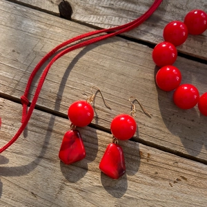 Dettaglio di orecchini pendenti in acrilico rosso con texture marmorea su base in legno