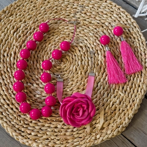 Dettaglio della collana di perle rosso rosa con fiore in tessuto e orecchini nappe
