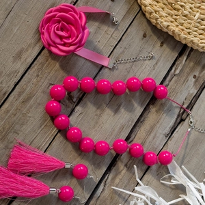 Dettaglio di parure rosa con girocollo rosa, collana di perle e orecchini con nappe