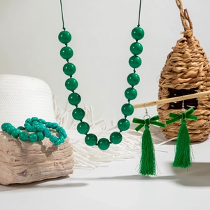 Dettaglio della collana di perle acriliche verdi e orecchini con fiocco e nappe