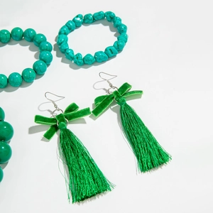 Dettaglio di orecchini con nappa verde e set di gioielli con perline coordinati