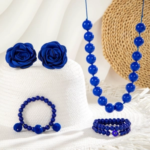 Dettaglio set gioielli rosa blu con collana di perle acriliche e bracciali assortiti