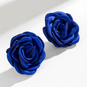 Dettaglio degli orecchini a rosa in raso blu scuro su sfondo bianco geometrico