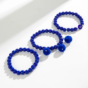 Set di tre braccialetti con perline blu scuro con ciondolo malocchio e pompon morbidi