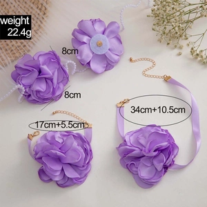 Dettaglio del set di accessori floreali in tessuto viola con nastri e catene dorate