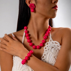 Dettaglio del set di collana, bracciale con perle magenta e orecchini a rosa sul modello