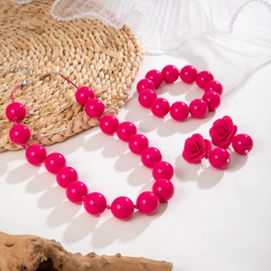 Dettaglio del set di gioielli con perle acriliche rosa, orecchini a rosa e collana coordinata